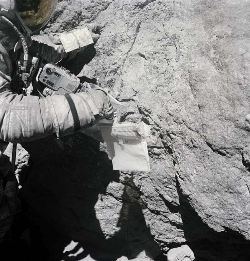 Astronaut Charles Duke examines surface of moon