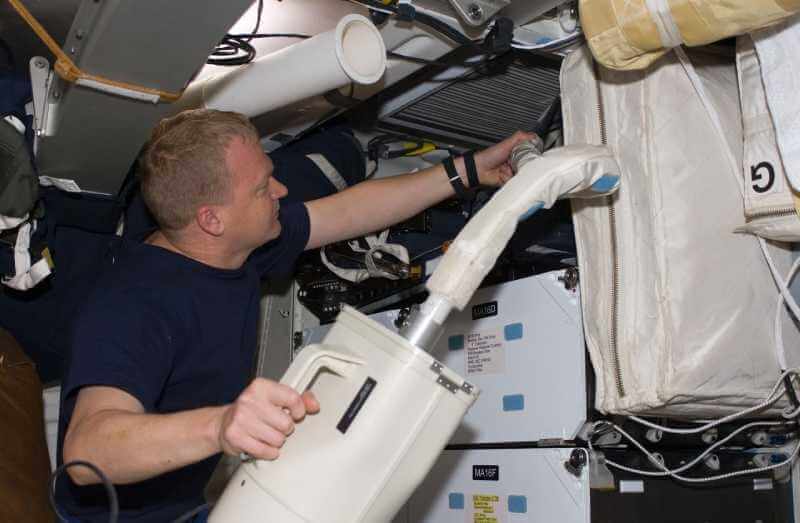 Astronaut using vacuum cleaner on the ISS