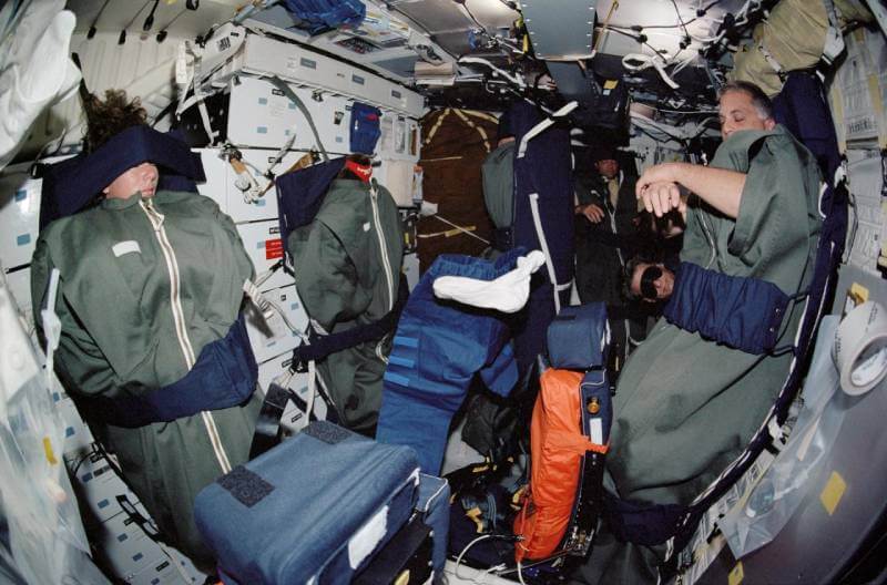 Astronauts sleeping in sleeping bags floating freely